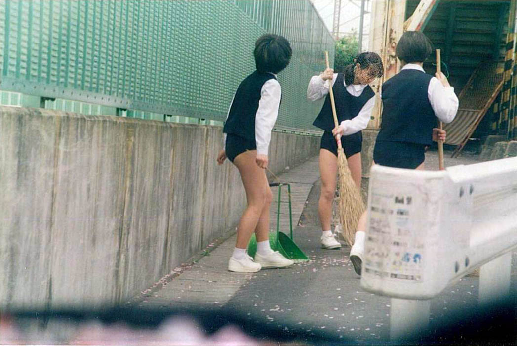 上が制服で下はブルマの女子3人が外で掃除をしています