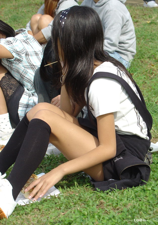 脚の細い女子が草の上に座っています