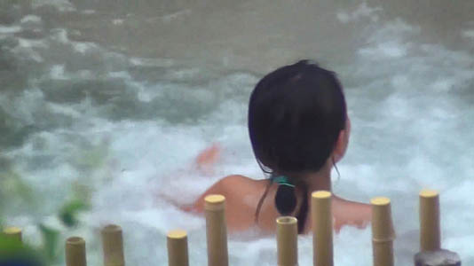 柵の向こうの露天の湯船に一人の女子が入っています